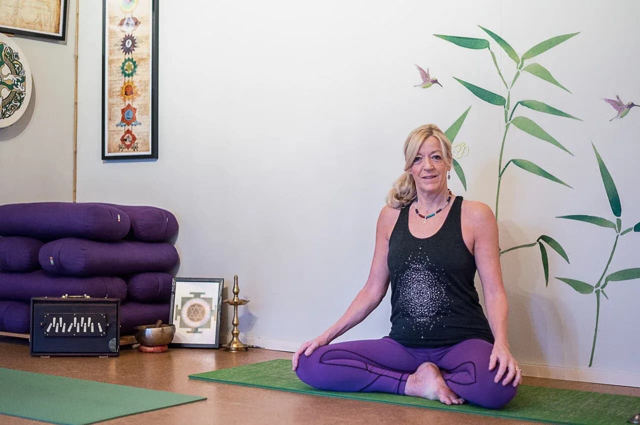 Vivien sitting on a yoga mat in The Yoga Den studio